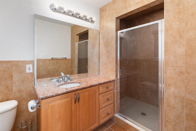 bathroom with walk in shower, tile patterned flooring, toilet, vanity, and tile walls