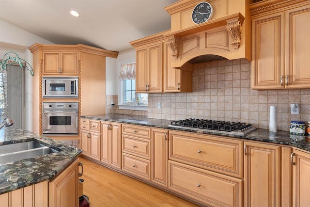 kitchen with tasteful backsplash, dark stone counters, stainless steel appliances, light brown cabinets, and light hardwood / wood-style flooring