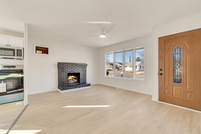 715 Eldredge Ave, North Cape May, NJ 08204 - unfurnished living room with light wood-style floors, baseboards, a ceiling fan, and a brick fireplace