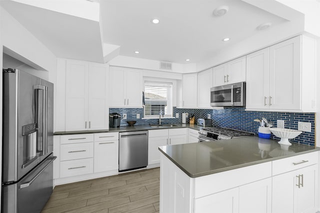 127 34th St, Avalon, NJ 08202 - kitchen featuring stainless steel appliances, a sink, a peninsula, dark countertops, and white cabinets