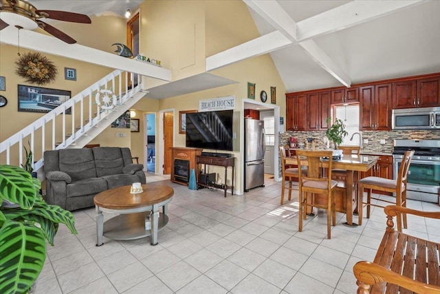 living area with light tile patterned flooring, a fireplace, a ceiling fan, stairs, and beamed ceiling