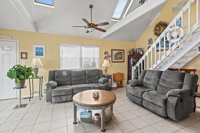 living room featuring a skylight, ceiling fan, light tile patterned floors, and stairway