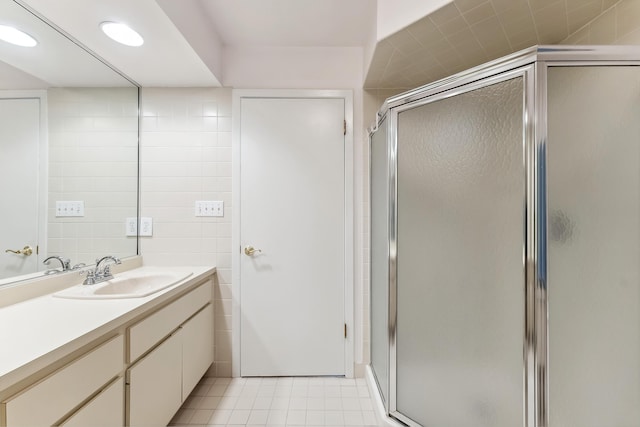 bathroom featuring a shower with door, vanity, and tile walls