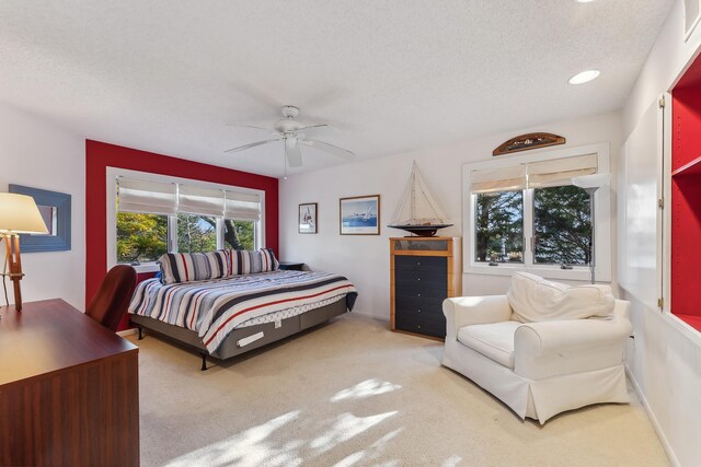 carpeted bedroom featuring ceiling fan and a textured ceiling