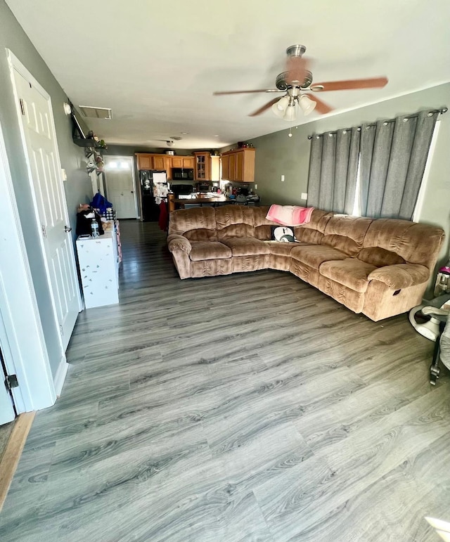 living room featuring visible vents, ceiling fan, and wood finished floors