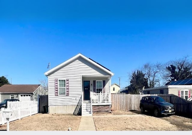 bungalow-style home featuring a porch, fence, and a garage