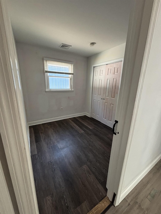 unfurnished bedroom with baseboards, a closet, visible vents, and dark wood-style flooring