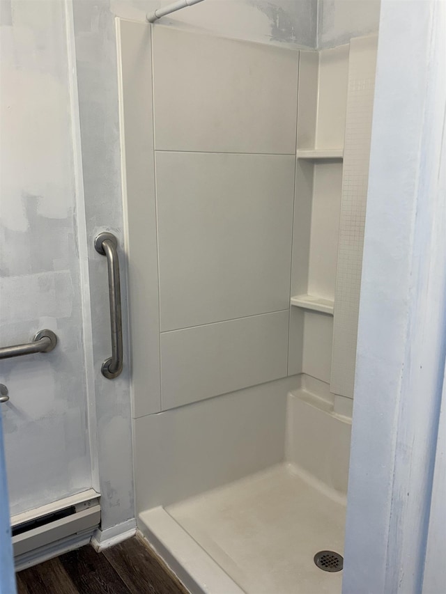 bathroom featuring a stall shower, baseboard heating, and wood finished floors