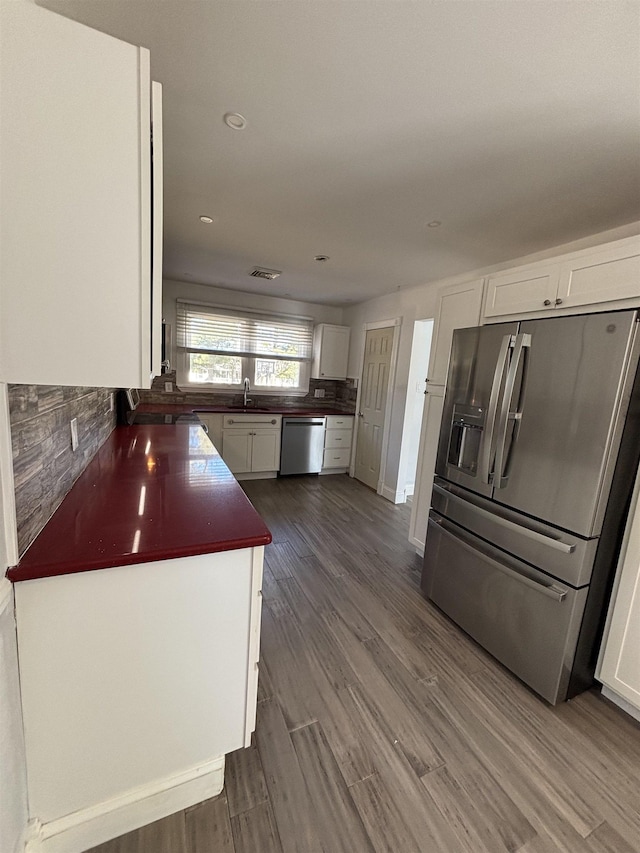 kitchen featuring dark countertops, appliances with stainless steel finishes, white cabinets, and a sink