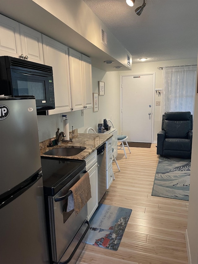 875 Plymouth Pl Unit 33, Ocean City, NJ 08226 - kitchen featuring appliances with stainless steel finishes, a sink, white cabinetry, light wood-style flooring, and light stone countertops