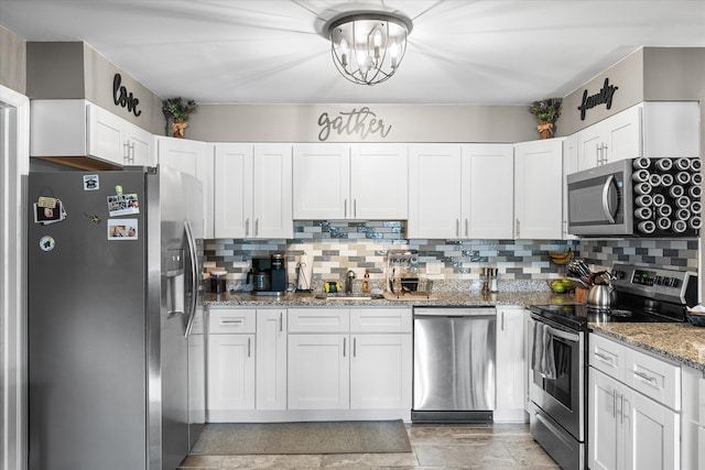 kitchen featuring appliances with stainless steel finishes, backsplash, white cabinets, and light stone counters