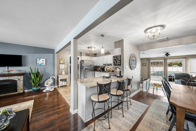 kitchen with stainless steel fridge with ice dispenser, dark hardwood / wood-style floors, kitchen peninsula, white cabinets, and backsplash