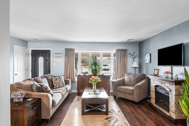 living room with a stone fireplace and dark hardwood / wood-style flooring