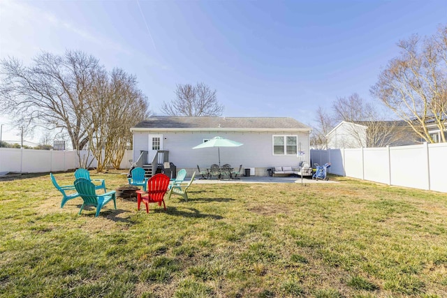 rear view of property featuring a fire pit, a fenced backyard, and a lawn