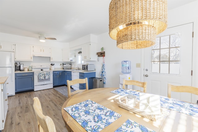 dining area with light wood-style flooring and ceiling fan with notable chandelier