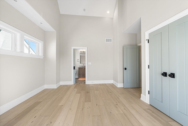 unfurnished bedroom with light hardwood / wood-style floors, a towering ceiling, and a closet