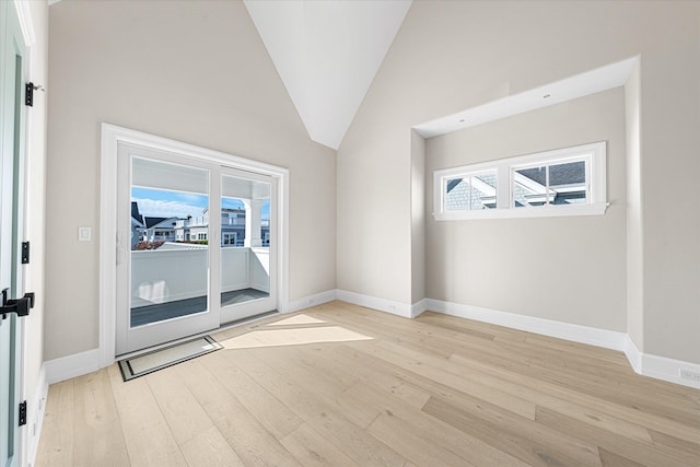 empty room featuring high vaulted ceiling and light hardwood / wood-style flooring