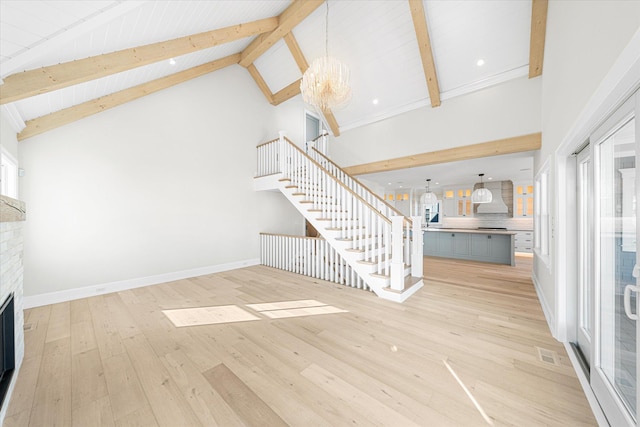 unfurnished living room featuring an inviting chandelier, beamed ceiling, light wood-type flooring, and high vaulted ceiling