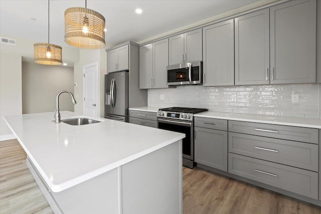 165 E Garfield Ave Unit 110, Wildwood, NJ 08260 - kitchen with appliances with stainless steel finishes, gray cabinetry, light wood finished floors, a kitchen island with sink, and light countertops