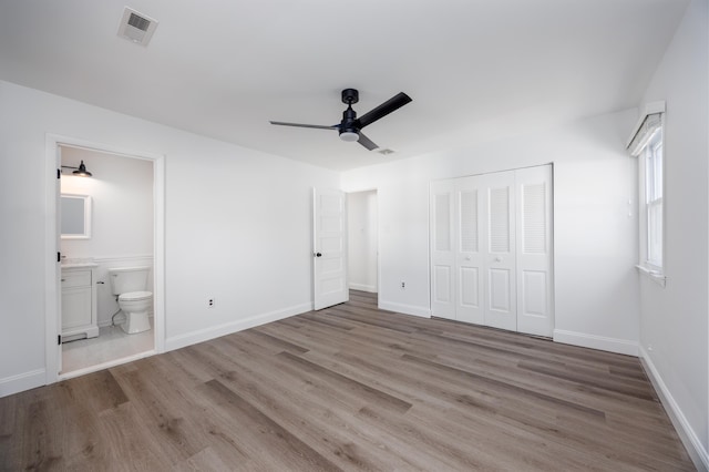 unfurnished bedroom featuring light hardwood / wood-style flooring, connected bathroom, ceiling fan, and a closet