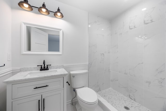 bathroom with tiled shower, vanity, and toilet