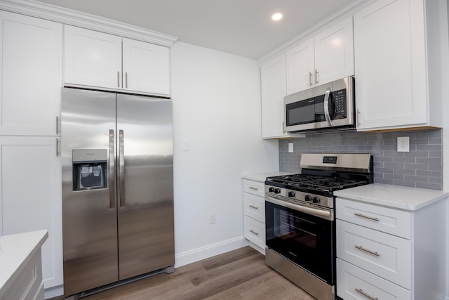 kitchen featuring white cabinetry, light stone counters, stainless steel appliances, light hardwood / wood-style floors, and decorative backsplash