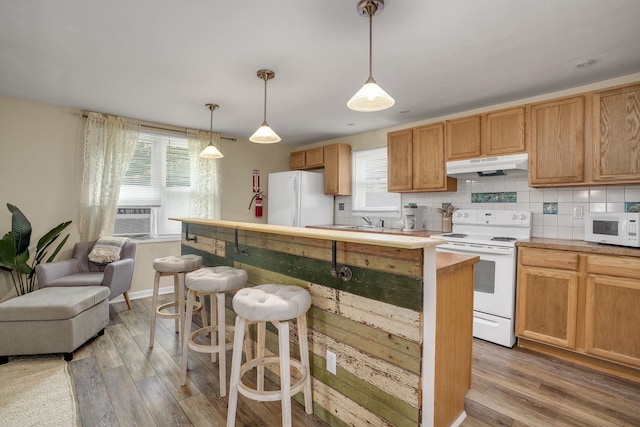 39 E Pacific Ave, Villas, NJ 08251 - kitchen with white appliances, under cabinet range hood, light wood-type flooring, a breakfast bar, and decorative backsplash