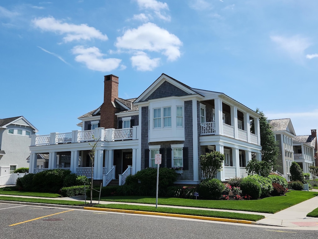 8700 1st Ave, Stone Harbor, NJ 08247 - view of front of house with a chimney, a balcony, uncovered parking, and a front lawn