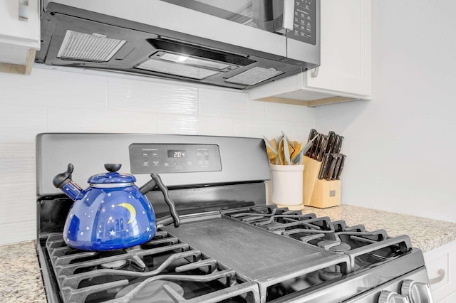 kitchen with stainless steel appliances, white cabinets, and tasteful backsplash