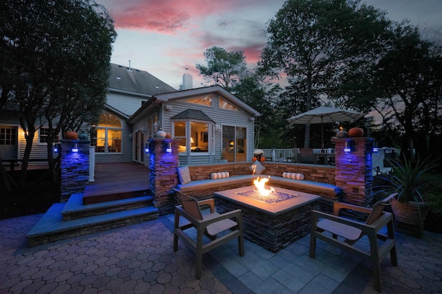 patio terrace at dusk featuring a deck and an outdoor fire pit