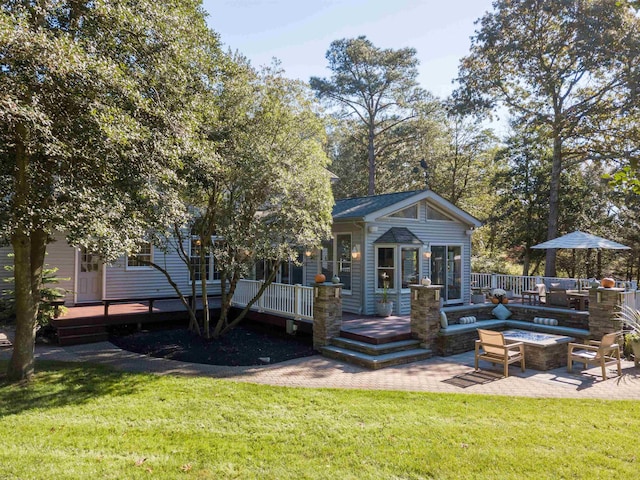 view of front of house with a fire pit, a patio area, a wooden deck, and a front lawn