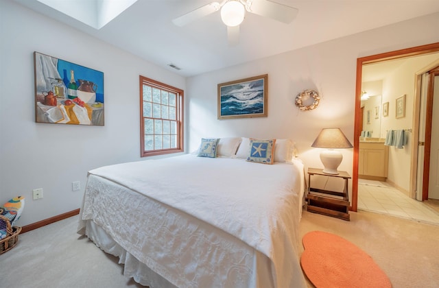 bedroom with connected bathroom, light colored carpet, and ceiling fan