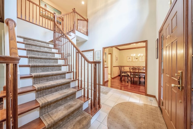 entryway featuring a towering ceiling, ornamental molding, and light tile patterned flooring