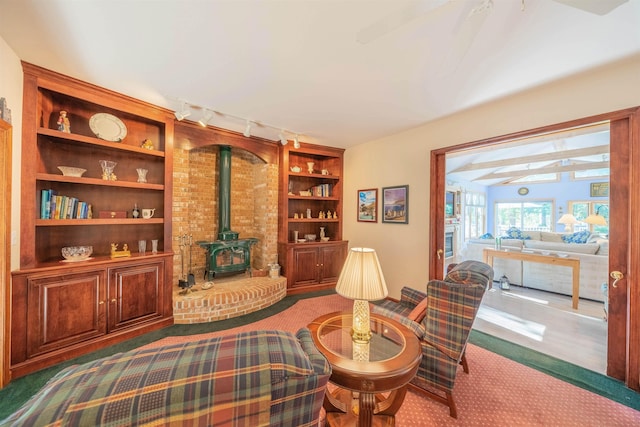 living area with carpet flooring, built in shelves, a wood stove, and rail lighting