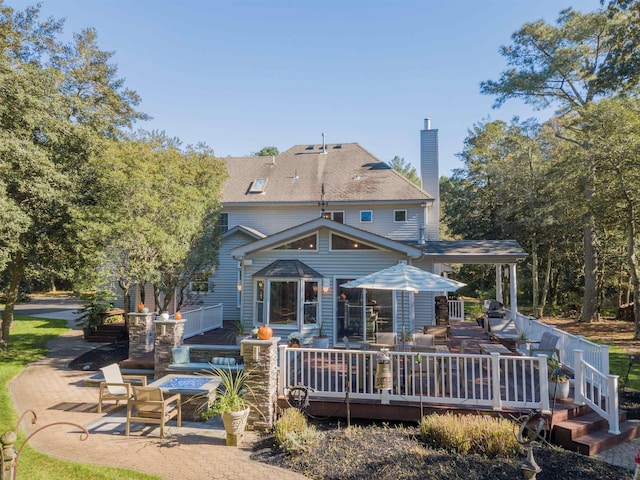 back of house featuring a wooden deck and a patio