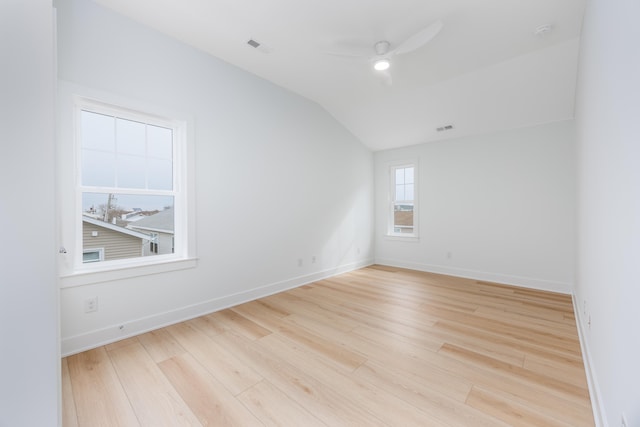 spare room with lofted ceiling, visible vents, a ceiling fan, baseboards, and light wood-type flooring