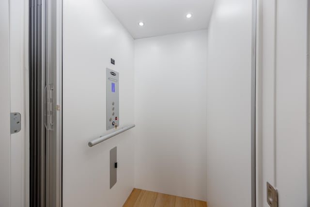 interior details featuring elevator, wood finished floors, and recessed lighting