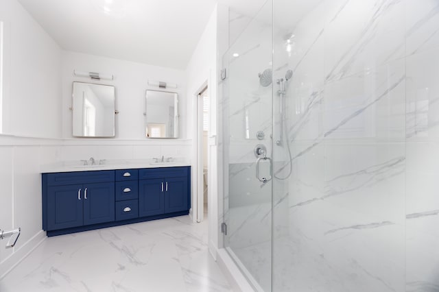 full bath with marble finish floor, wainscoting, a sink, and a marble finish shower