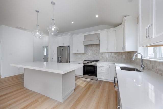 kitchen featuring stainless steel appliances, light countertops, custom range hood, white cabinetry, and a sink