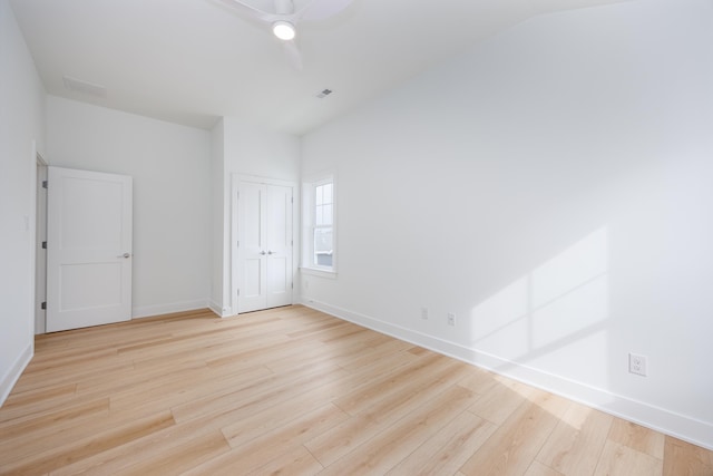 unfurnished bedroom featuring lofted ceiling, a ceiling fan, baseboards, visible vents, and light wood-style floors