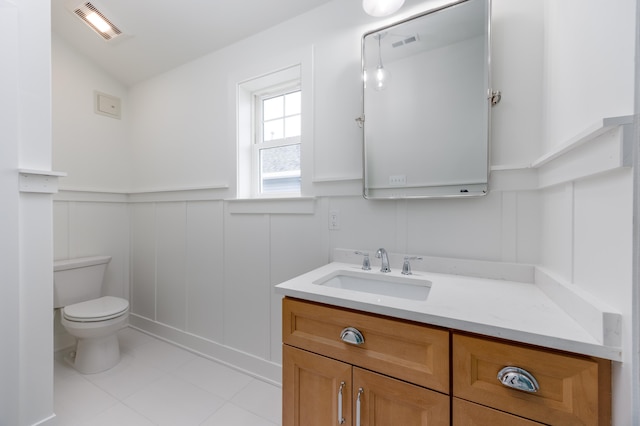 bathroom with a wainscoted wall, visible vents, a decorative wall, toilet, and vanity