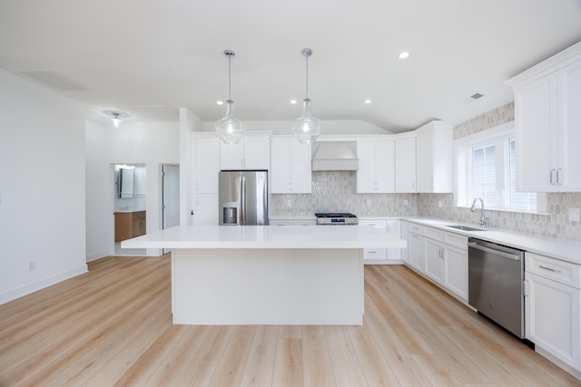 kitchen with white cabinets, a center island, stainless steel appliances, light countertops, and a sink