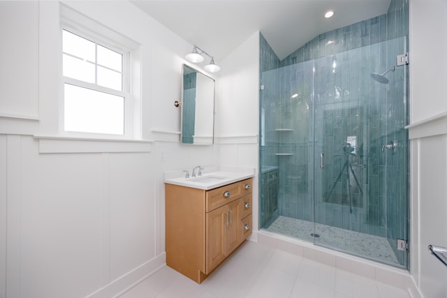 full bathroom with lofted ceiling, tile patterned flooring, vanity, wainscoting, and a stall shower