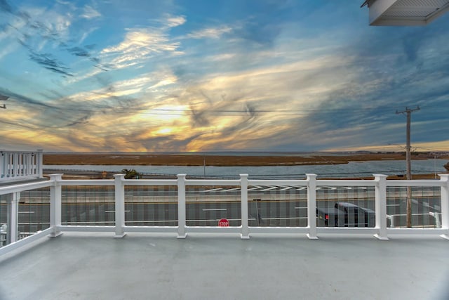 patio terrace at dusk with a water view and a balcony