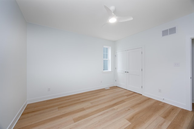 unfurnished room with baseboards, light wood finished floors, visible vents, and a ceiling fan