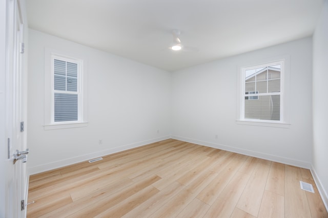 unfurnished room with light wood-style floors, visible vents, and baseboards