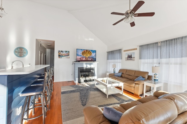 living room with high vaulted ceiling, sink, hardwood / wood-style floors, and ceiling fan