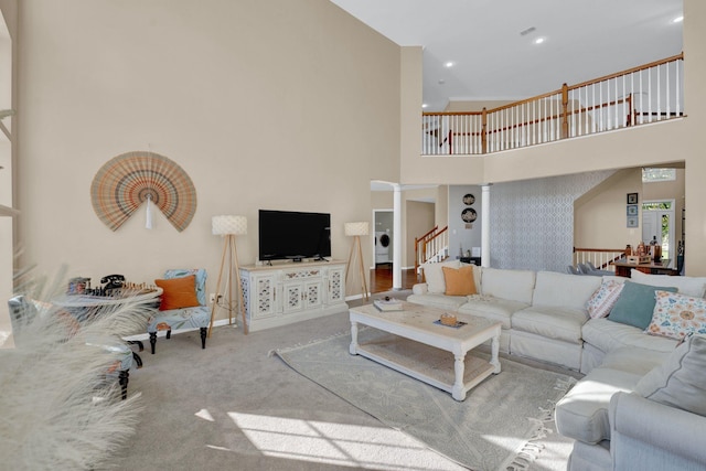 carpeted living room with ornate columns, a high ceiling, and washer / dryer