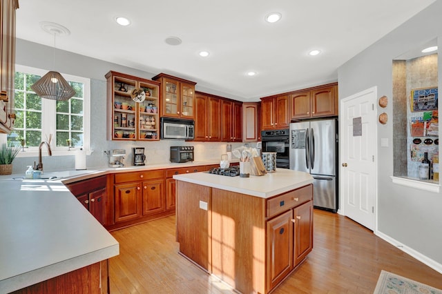 kitchen with sink, stainless steel appliances, light hardwood / wood-style floors, decorative light fixtures, and a kitchen island