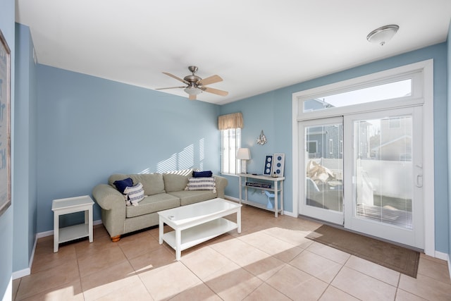 living area with light tile patterned floors, baseboards, and a ceiling fan